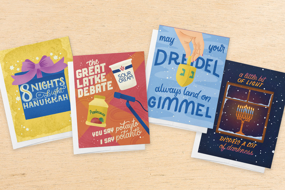 an array of illustrated Hanukkah cards on a wood table