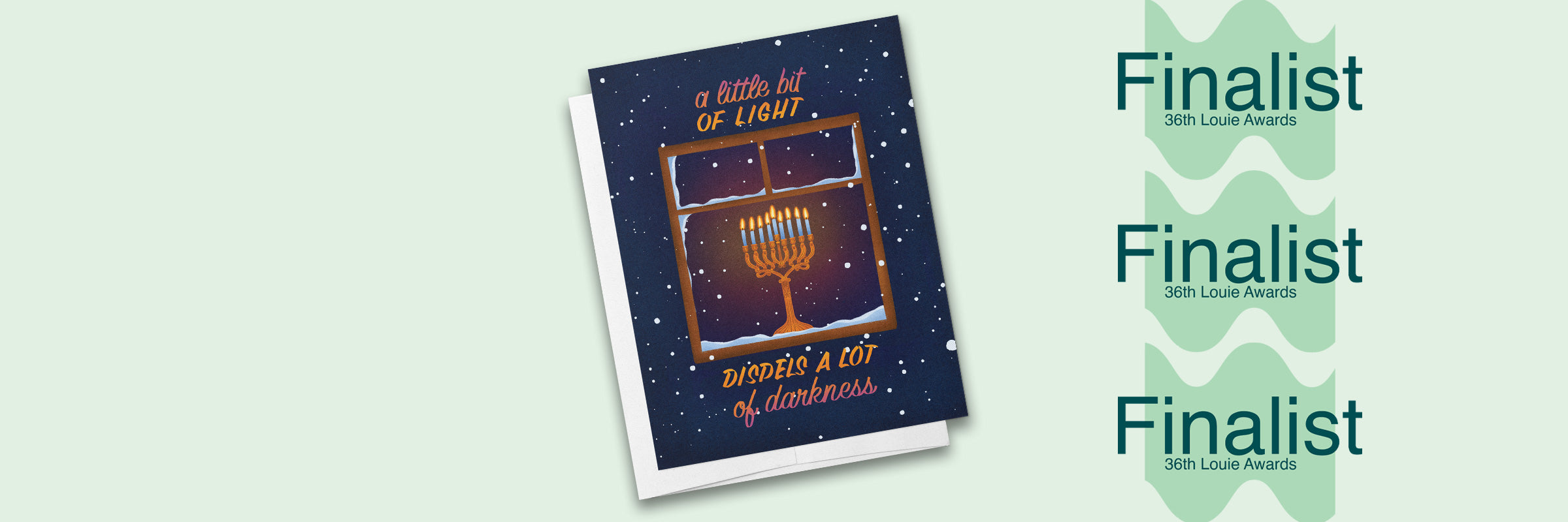 greeting card of a menorah in a window with text "a little bit of light dispels a lot of darkness" and a banner "finalist 36th Louie Awards"