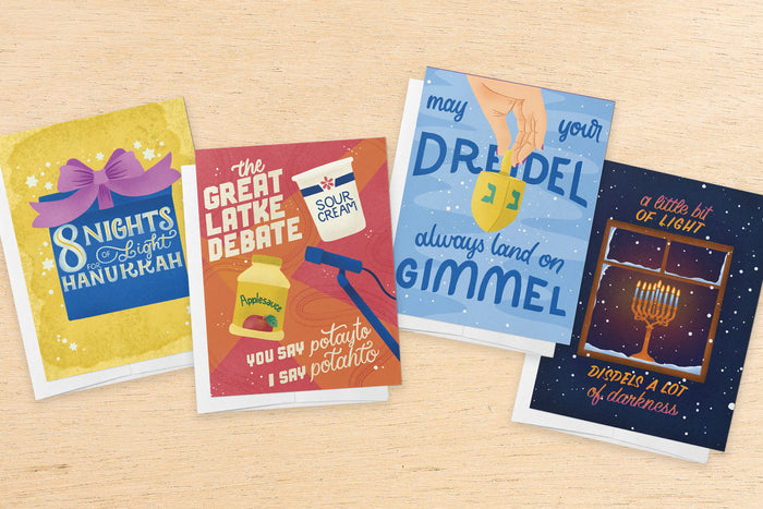 an array of illustrated Hanukkah cards on a wood table