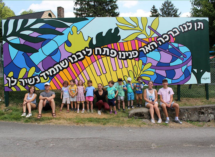 Children posing in front of a freestanding camp mural