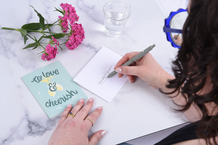 A woman addressing an envelope, and a greeting card that says 