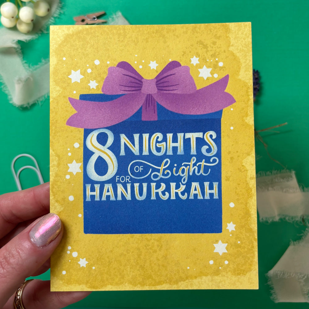 Card with '8 Nights of Light for Hanukkah' text and purple bow on yellow background