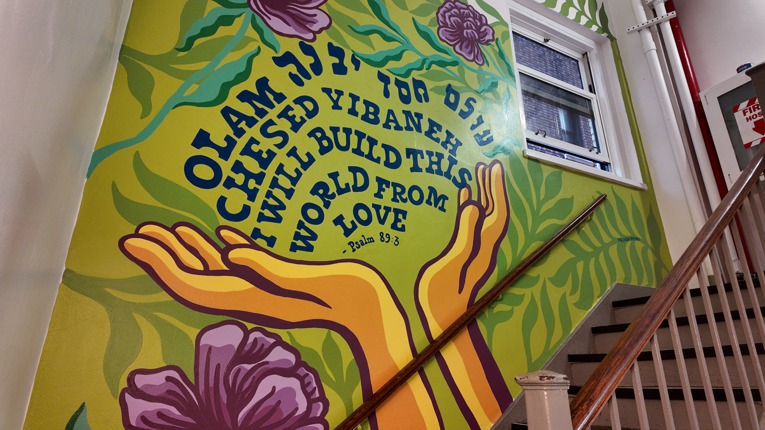 Colorful mural with hands and text on a wall in a stairwell