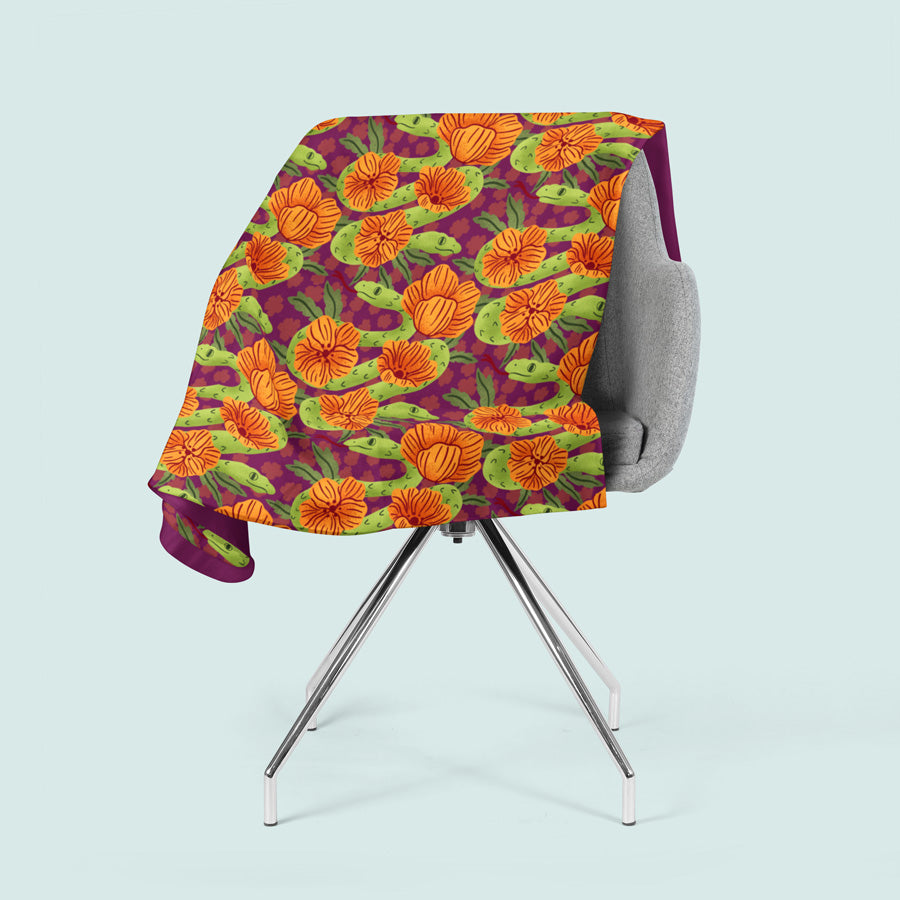 Chair with a colorful blanket featuring orange flowers and green leaves on a light blue background