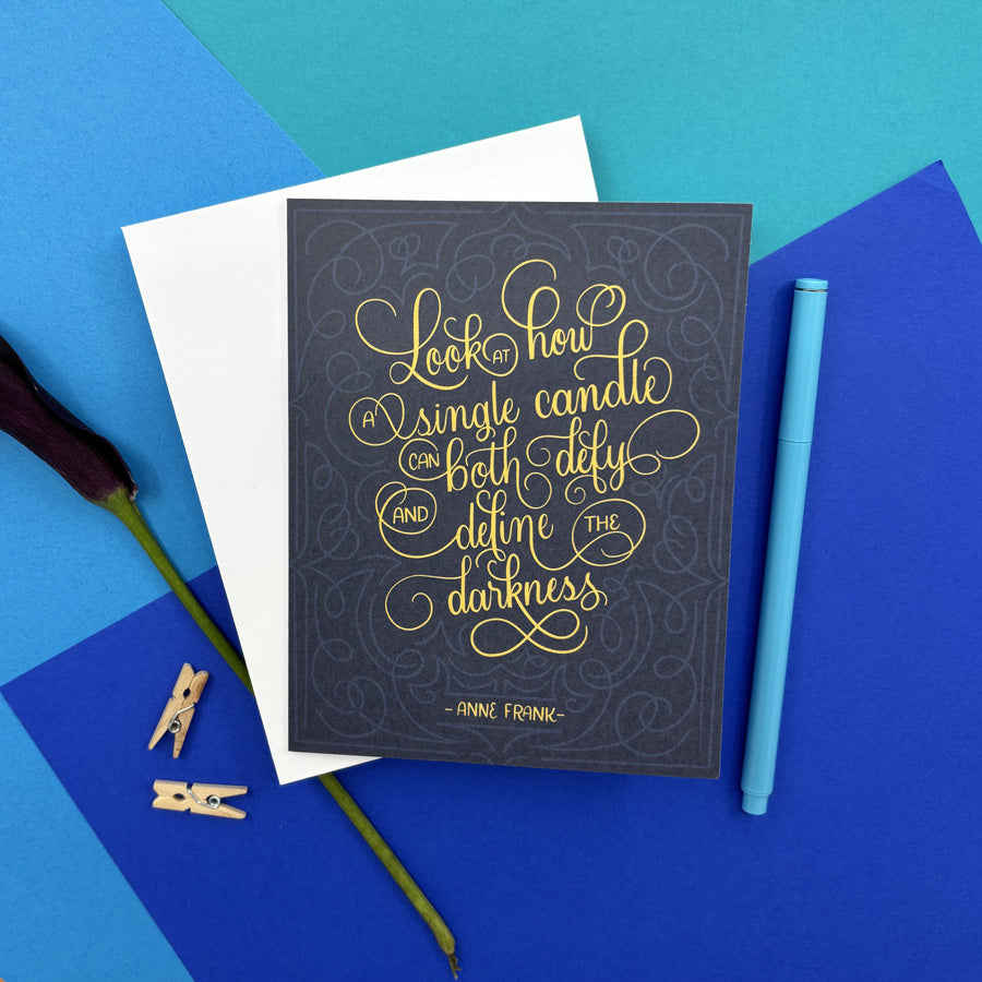 hanukkah card with Anne Frank quote "look at how a single candle can both defy and define the darkness" on a colorful background