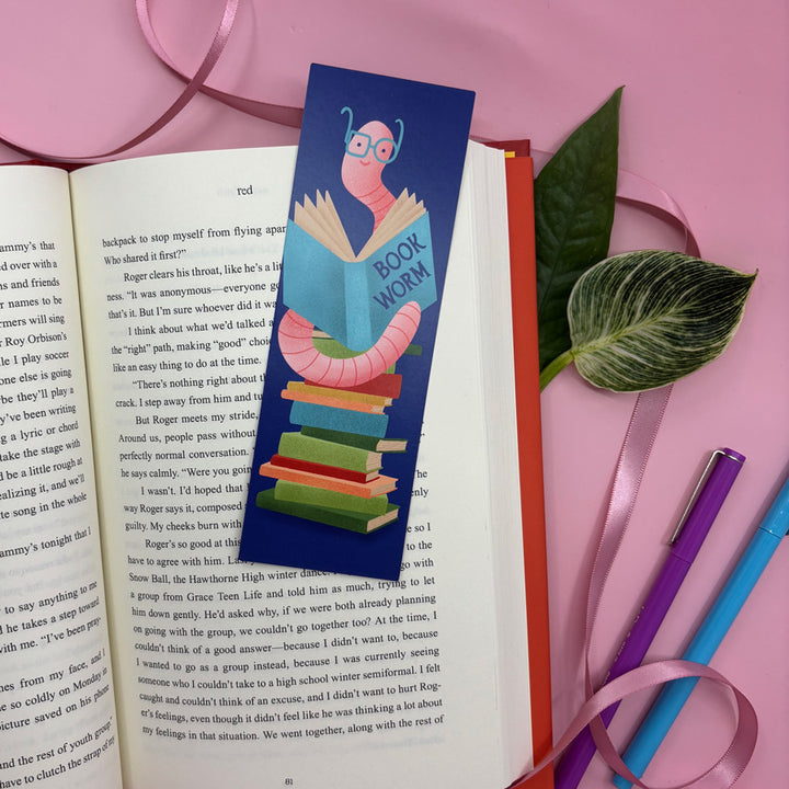 Colorful bookmark with a cartoon worm reading a book on an open book with pink background