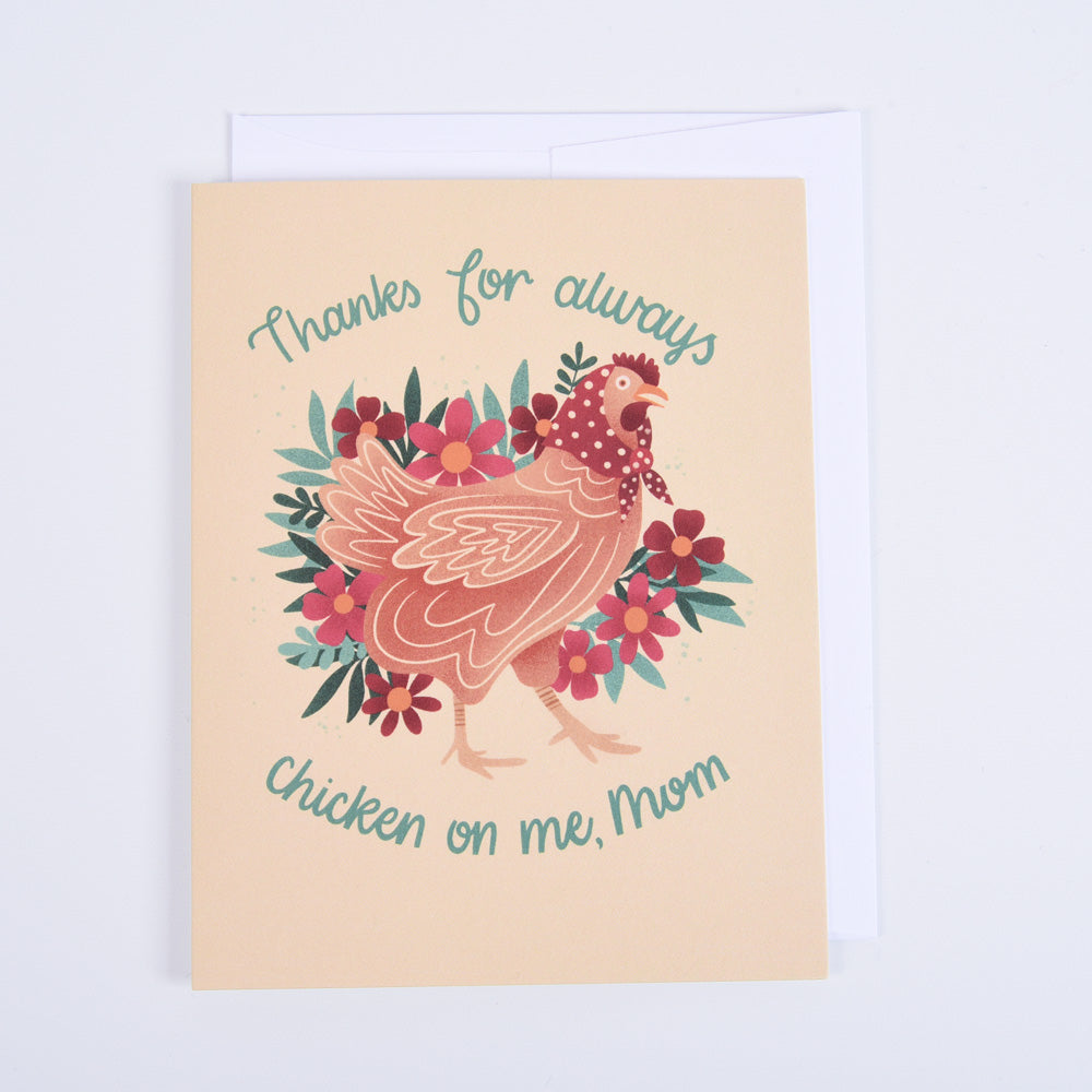 A greeting card with a colorful illustration of a chicken surrounded by flowers  with a message "thanks for chicken on me, mom"