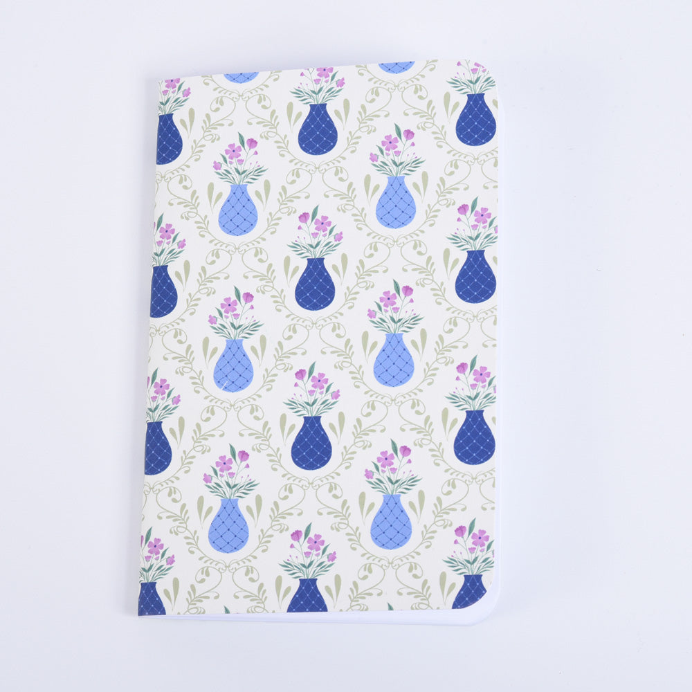 small pocket notebook with a pattern of blue vases and purple flowers on a sage green background