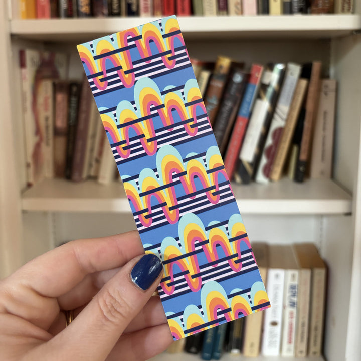 Colorful patterned bookmark held in front of a bookshelf