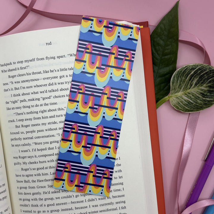 Colorful patterned bookmark on an open book with a pink background