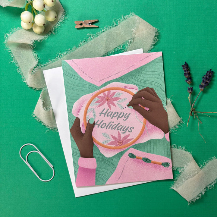 Greeting card with hands embroidery 'Happy Holidays' on a green background
