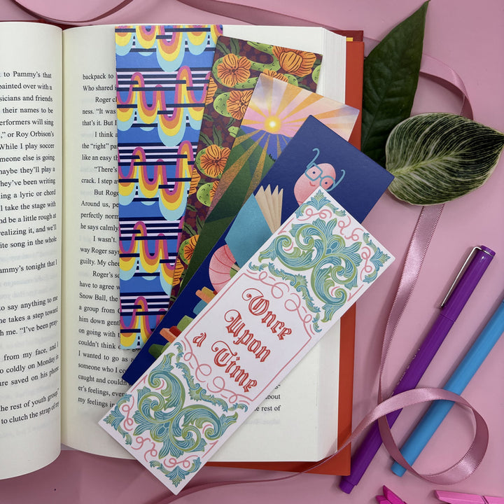 5 colorful bookmarks fanned out in an open book on a pink background