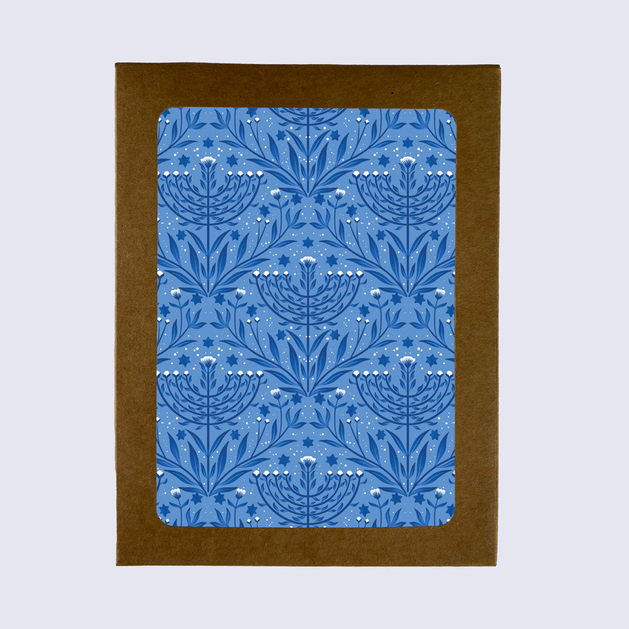 A folded greeting card with a blue floral menorah pattern, paired with a white envelope.