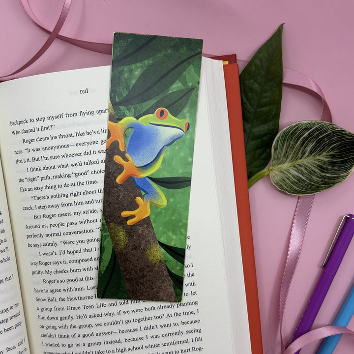 Colorful frog bookmark on a book with pink ribbon and green leaves