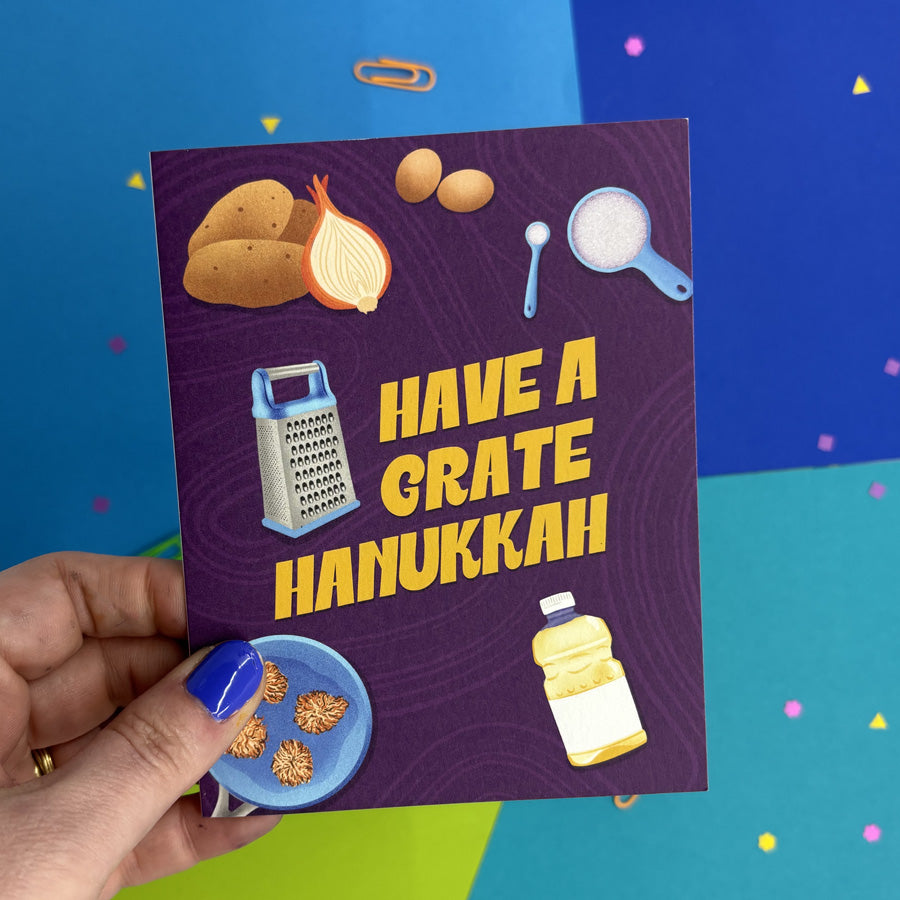 hand holding a Hanukkah card with illustrated potato latke ingredients and text "have a grate hanukkah"