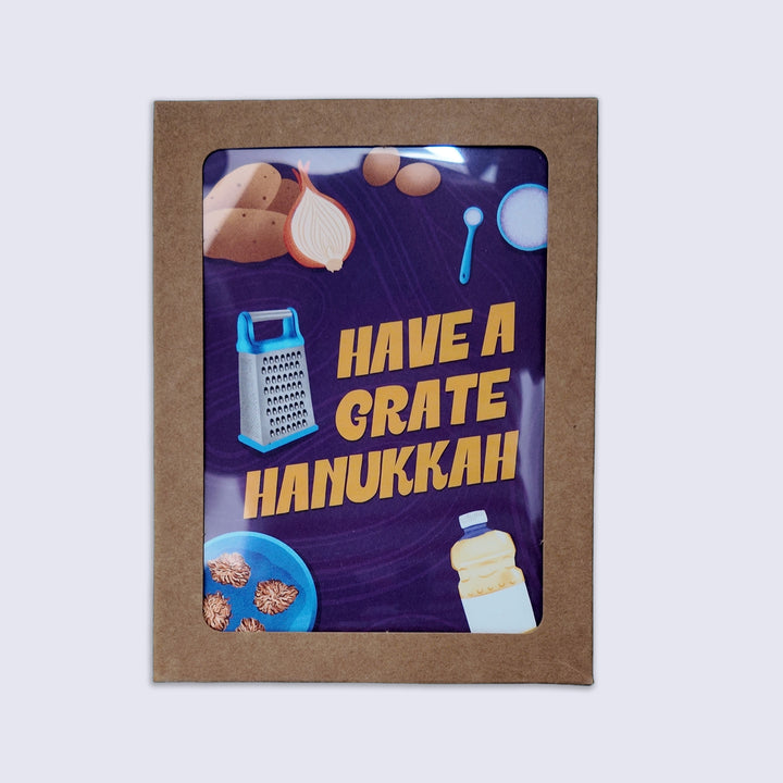 a kraft box set of greeting cards with lettering "have a grate hanukkah" and illustrations of latke ingredients including a grater, onions, potatoes, oil, and a measuring cup