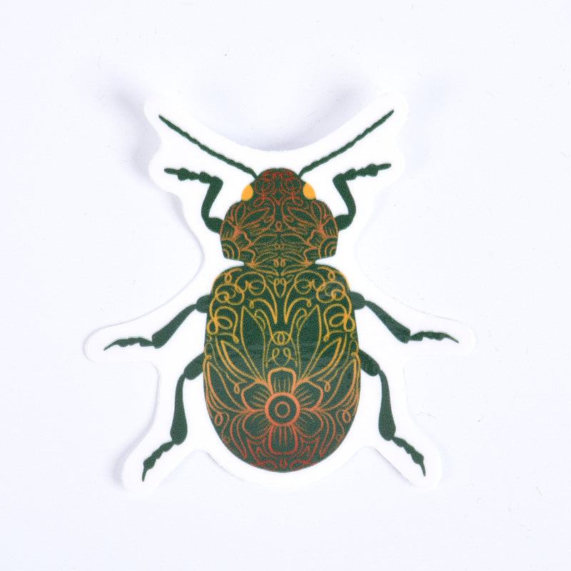 A sticker depicting a green beetle with floral-like patterns on its body.