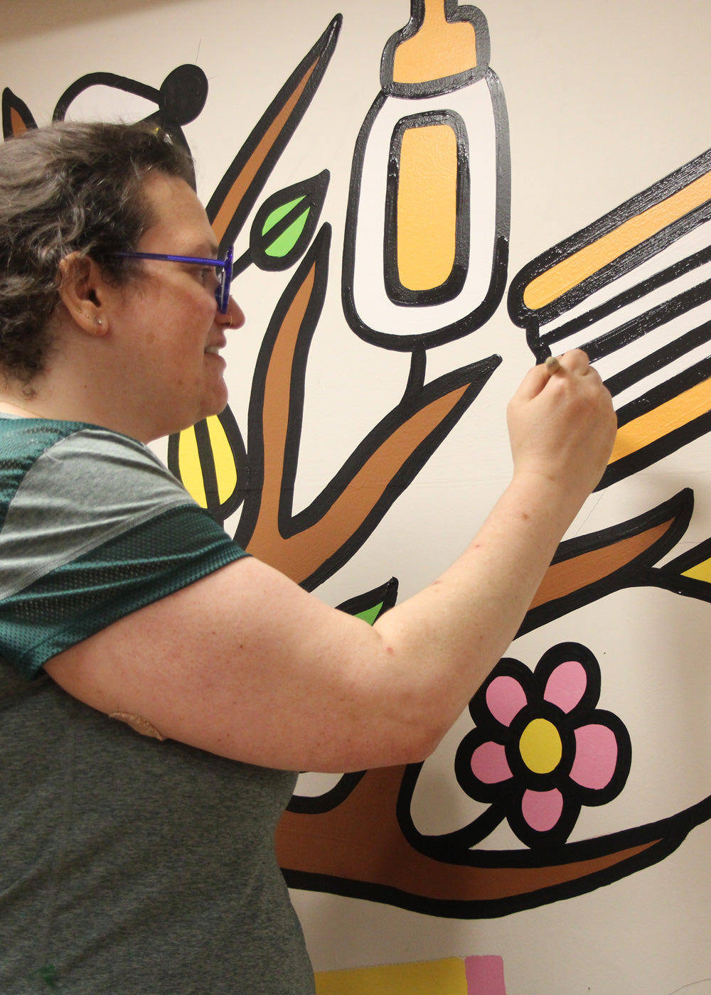 Person painting a colorful mural on a school wall