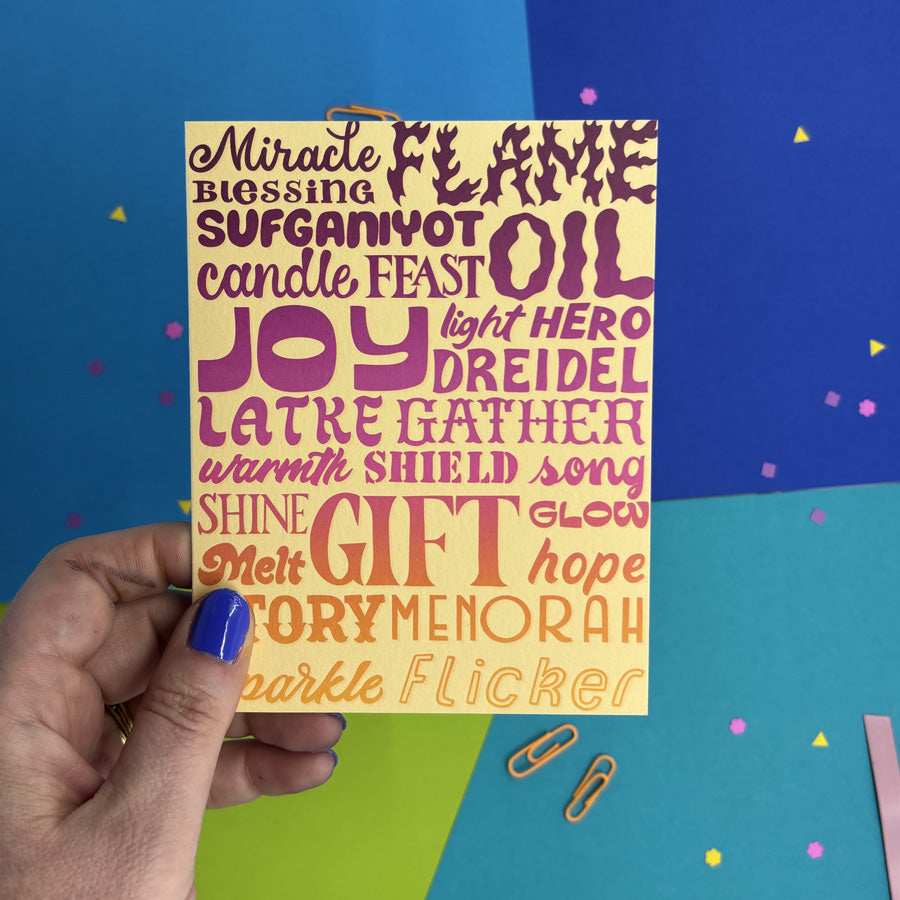 hand holding a hanukkah card with colorful holiday words 