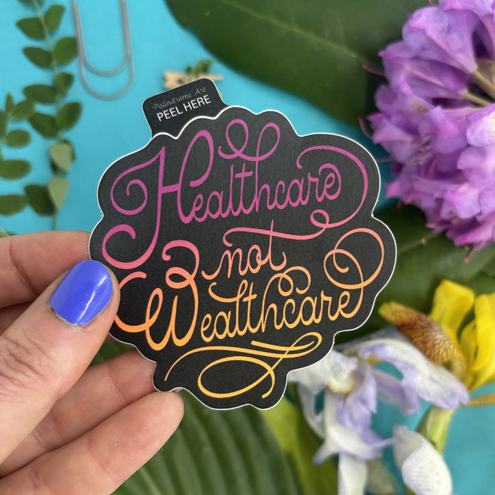 Hand holding a sticker with 'Healthcare not Wealthcare' text against a floral background