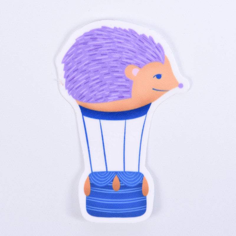 A sticker depicting a cartoon hedgehog riding a hot air balloon, with a blue and white color scheme and a purple hedgehog head.