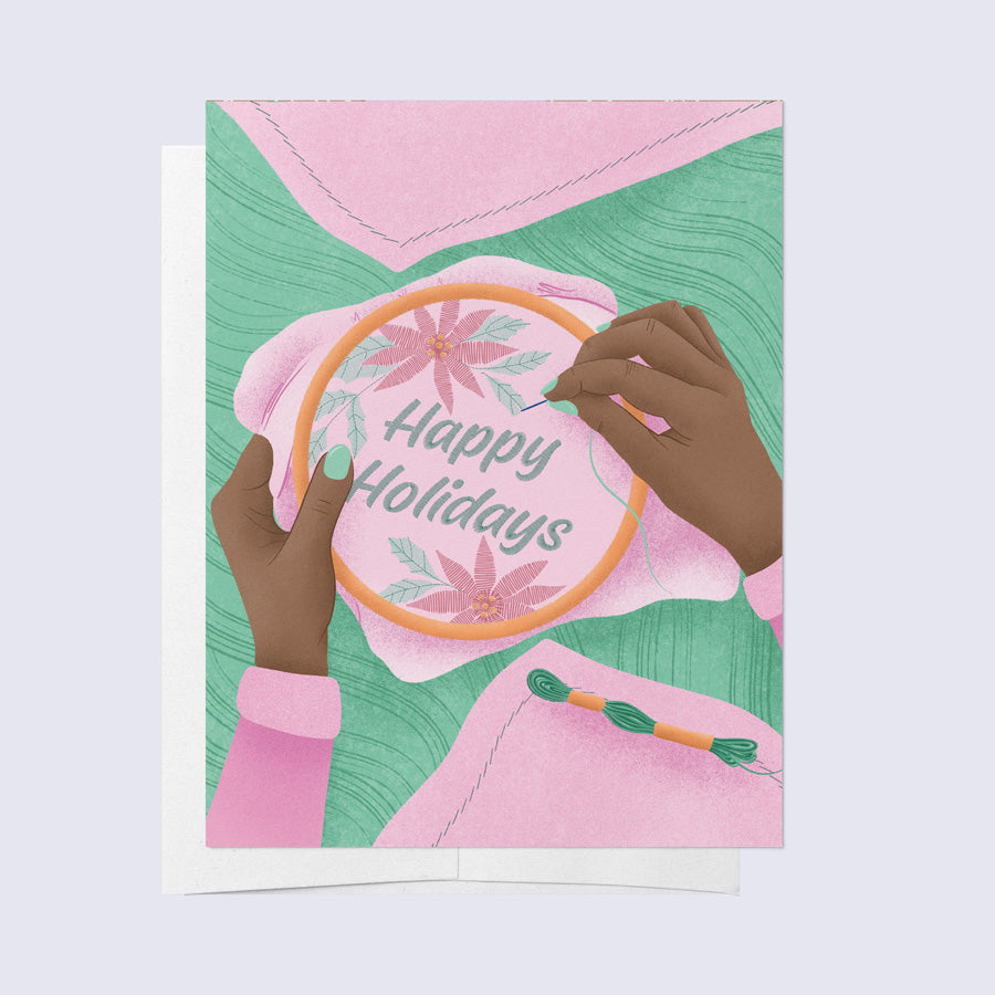 a greeting card of a person embroidering a happy holidays message