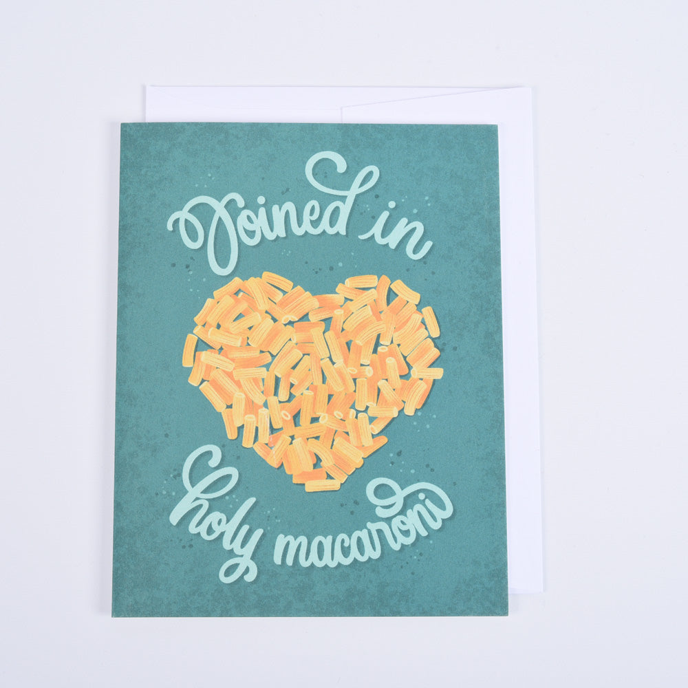 A folded greeting card with a green background featuring a stylized text and a heart-shaped macaroni illustration. The text reads "joined in holy macaroni"