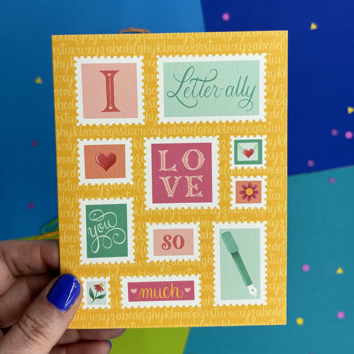 hand holding greeting card with illustrated stamps that says "I letter-ally love you so much"
