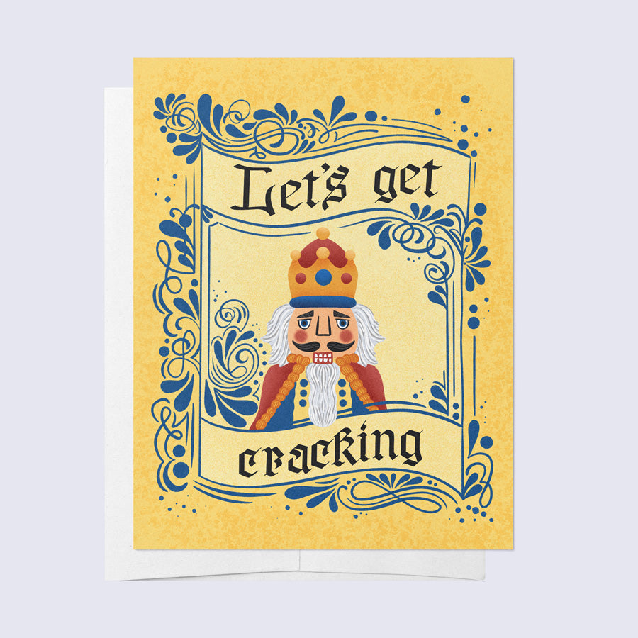 Greeting card with a cartoonish nutcracker character in a crown and robe, with the phrase 'Let's Get Cracking' 