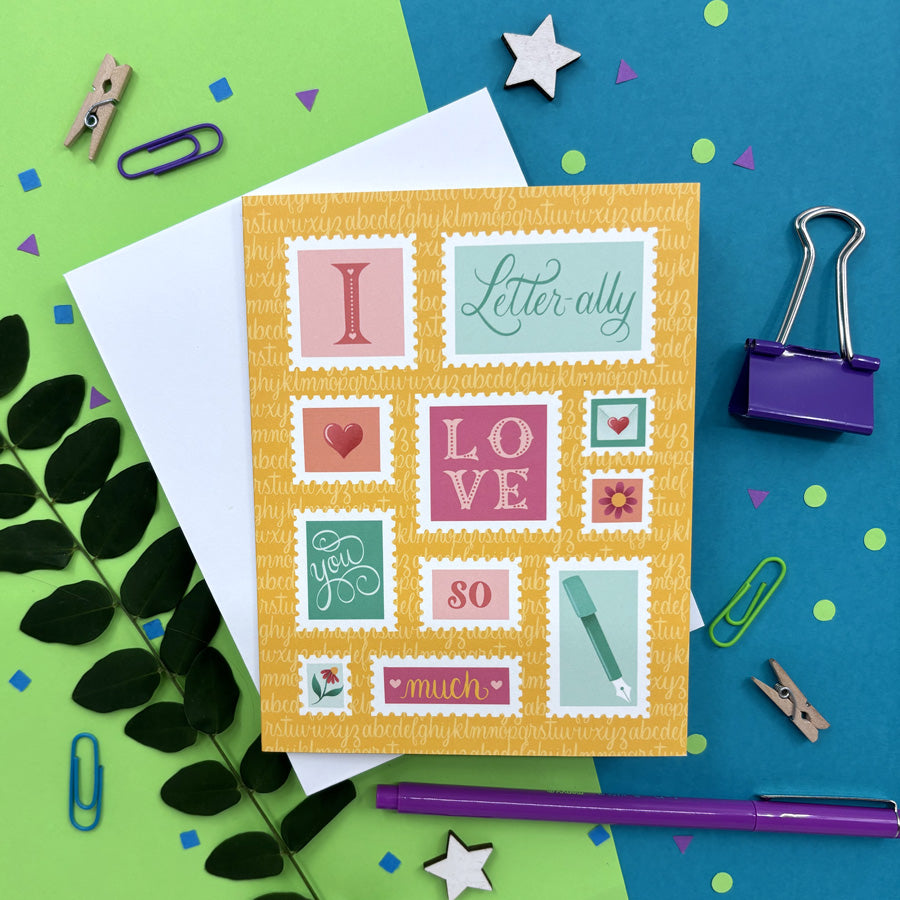 greeting card with illustrated stamps that says "I letter-ally love you so much" on a colorful background ith stationery items