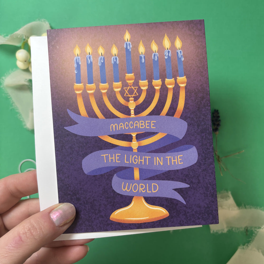 Card with Menorah illustration and banner that says "maccabee the light in the world"