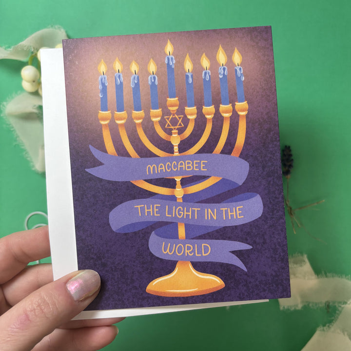 Card with Menorah illustration and banner that says "maccabee the light in the world"