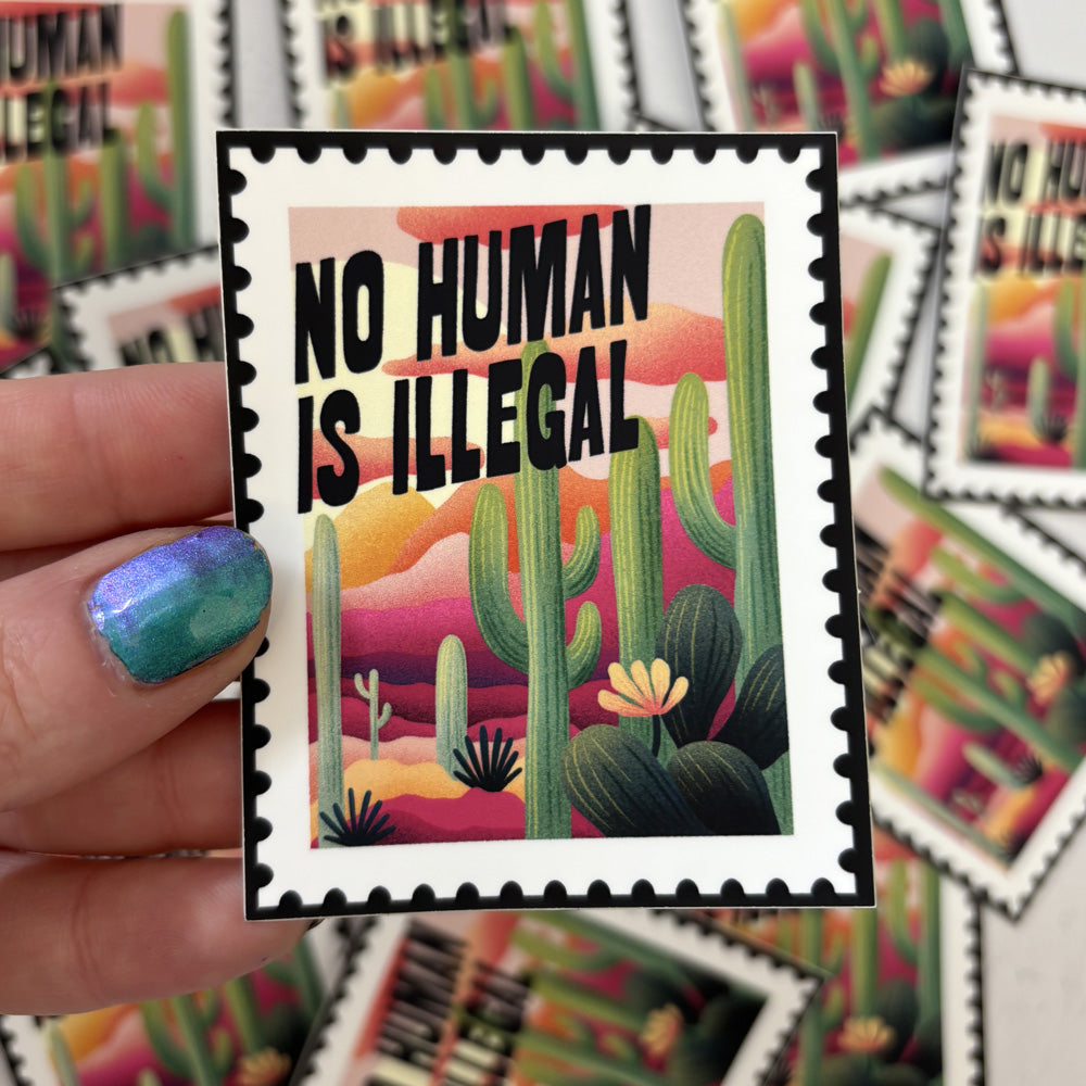 Sticker with cactus design and 'No Human Is Illegal' text held by a hand.
