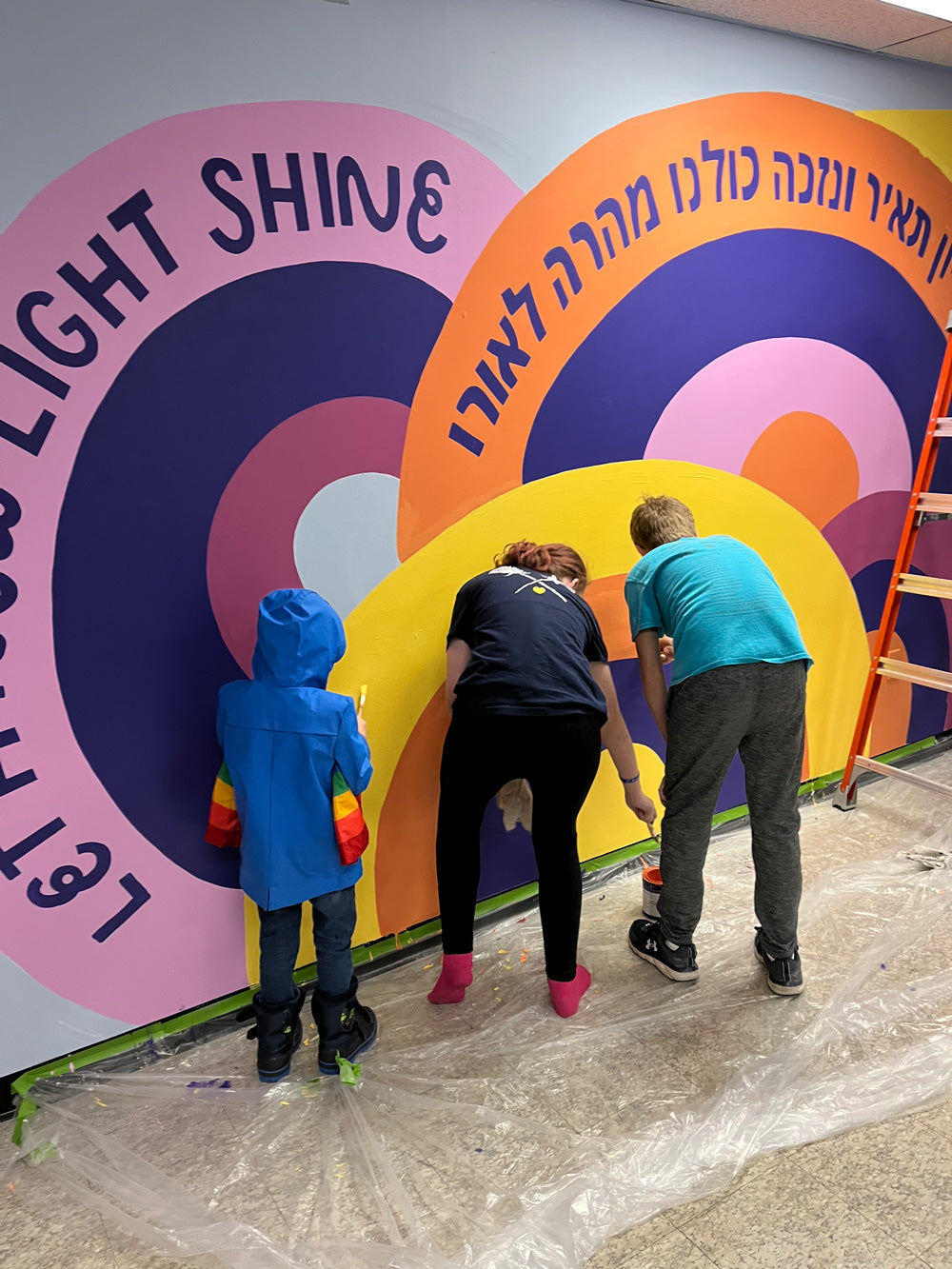 kids painting a colorful mural with hebrew letters
