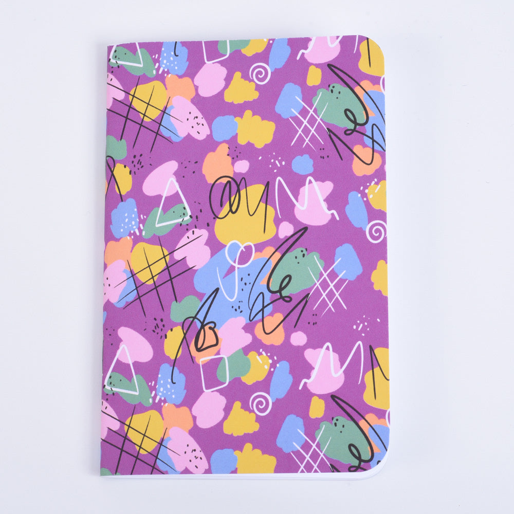 A pocket notebook with a vibrant pink, yellow, green, and blue abstract pattern on a purple background.