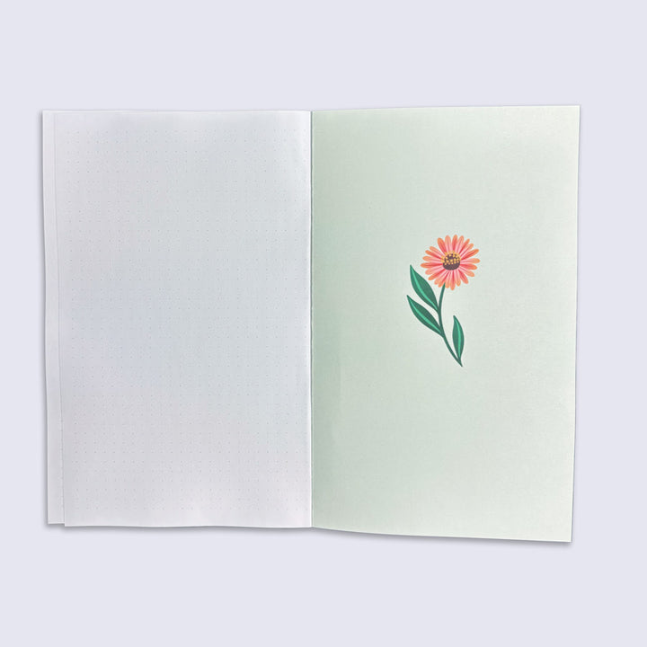 Open notebook with a pink flower illustration on a light green page