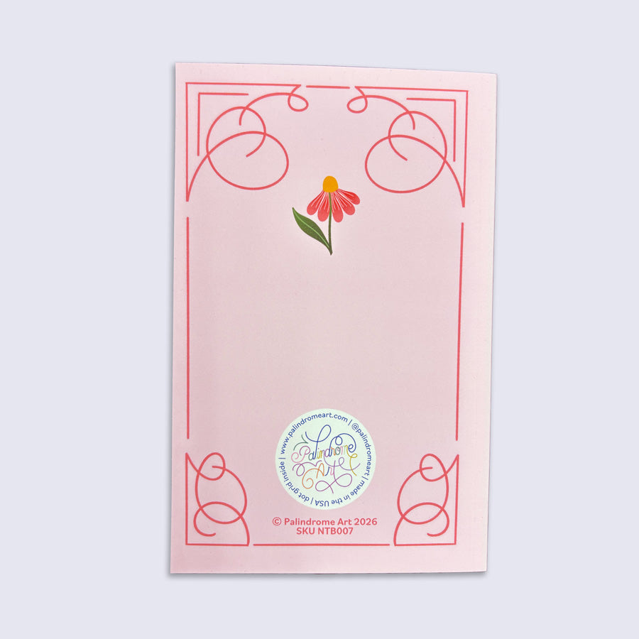 Pink journal with floral design and a logo on a light gray background