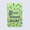 small green pocket notebook with medieval lettering that says "read banned books" with floral illustrations