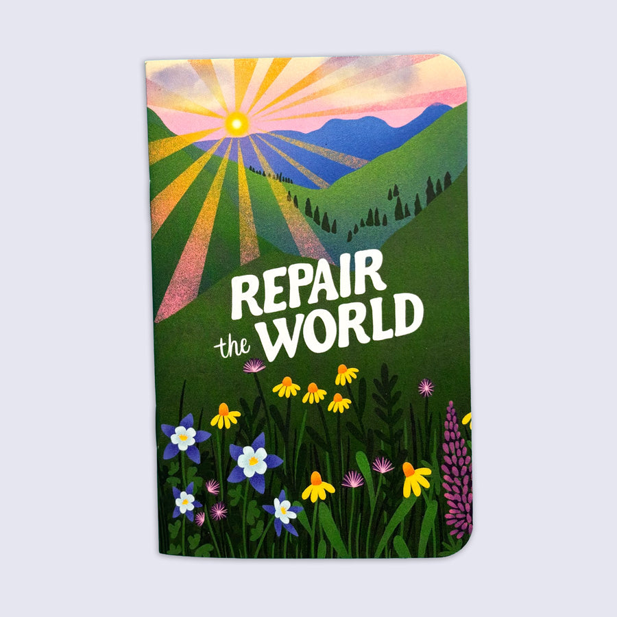 A notebook with rounded corners featuring a colorful landscape illustration of mountains, a rising sun, and wildflowers, with the text 'REPAIR the WORLD' printed on the front