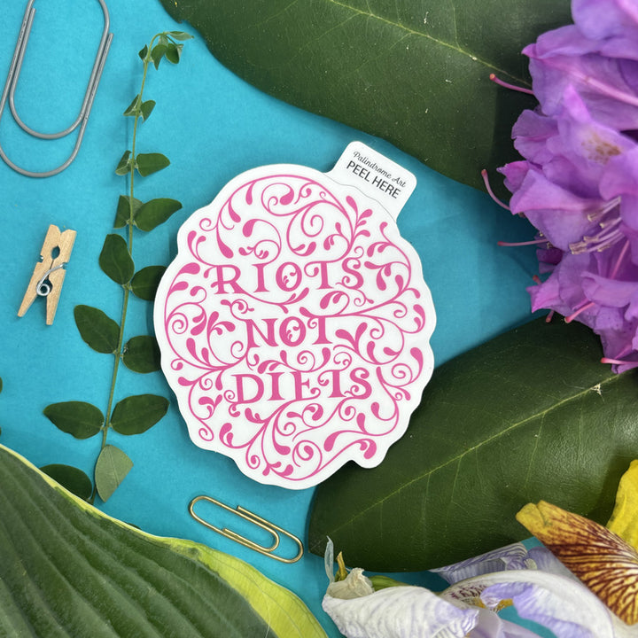 Sticker with 'Riots Not Diets' text on a blue background with leaves and flowers.