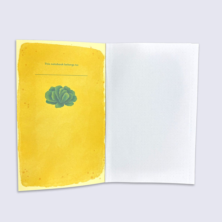 Notebook with yellow cover and green lettuce illustration on a light gray background