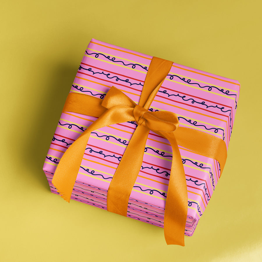 Gift box with pink striped wrapping paper and orange ribbon on a yellow background