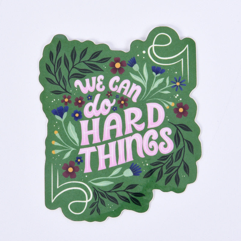 floral sticker with lettering "we can do hard things" on a green background