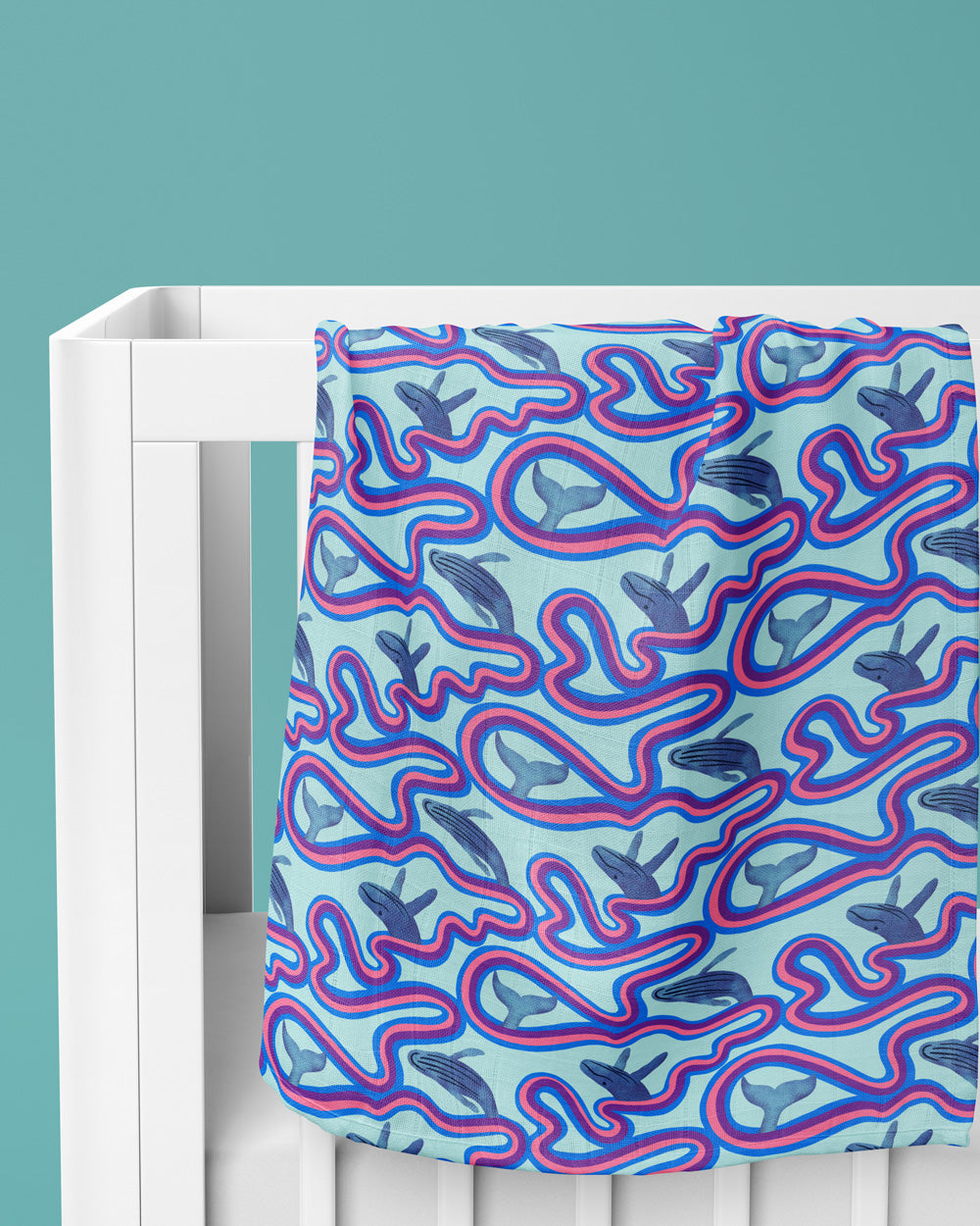 Crib with a blue and pink patterned fitted sheet on a teal background