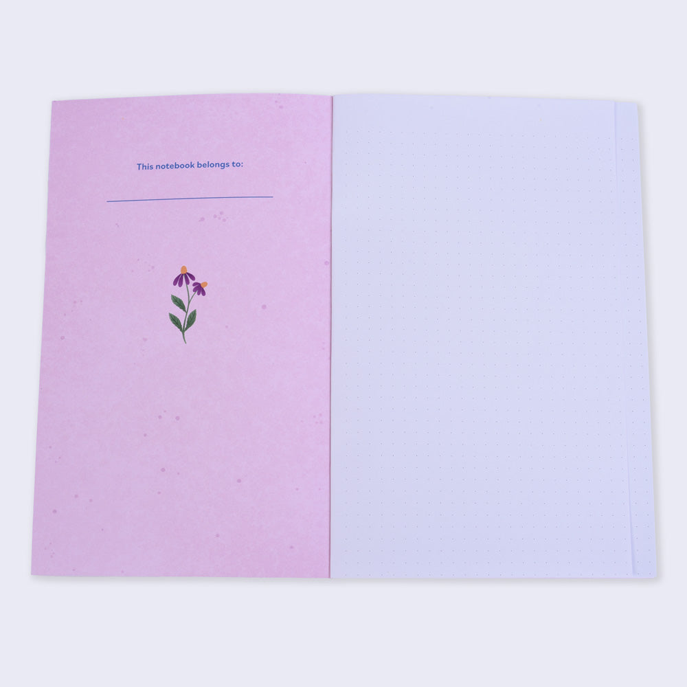 open notebook with dot grid pages and left inside cover is pink with a small flower and text "this notebook belongs to"